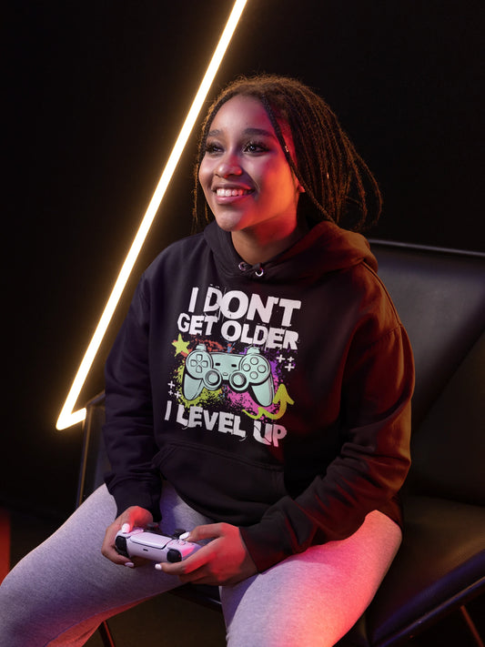 I Don’t Get Older, I Level Up | Gamer Hoodie im Neon-Splash-Style – schwarz Hoodie als weiblich-Mockup, modernes Gaming-Design und hochwertiges Produktfoto.