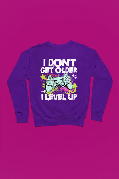 I Don’t Get Older – I Level Up | Gamer Pullover im Neon-Splash-Design – lila Pullover als Flatlay-Mockup, hochwertiges Nerd- & Gaming-Design Produktfoto.