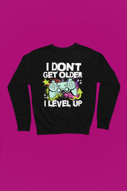 I Don’t Get Older – I Level Up | Gamer Pullover im Neon-Splash-Design – schwarz Pullover als Flatlay-Mockup, hochwertiges Nerd- & Gaming-Design Produktfoto.