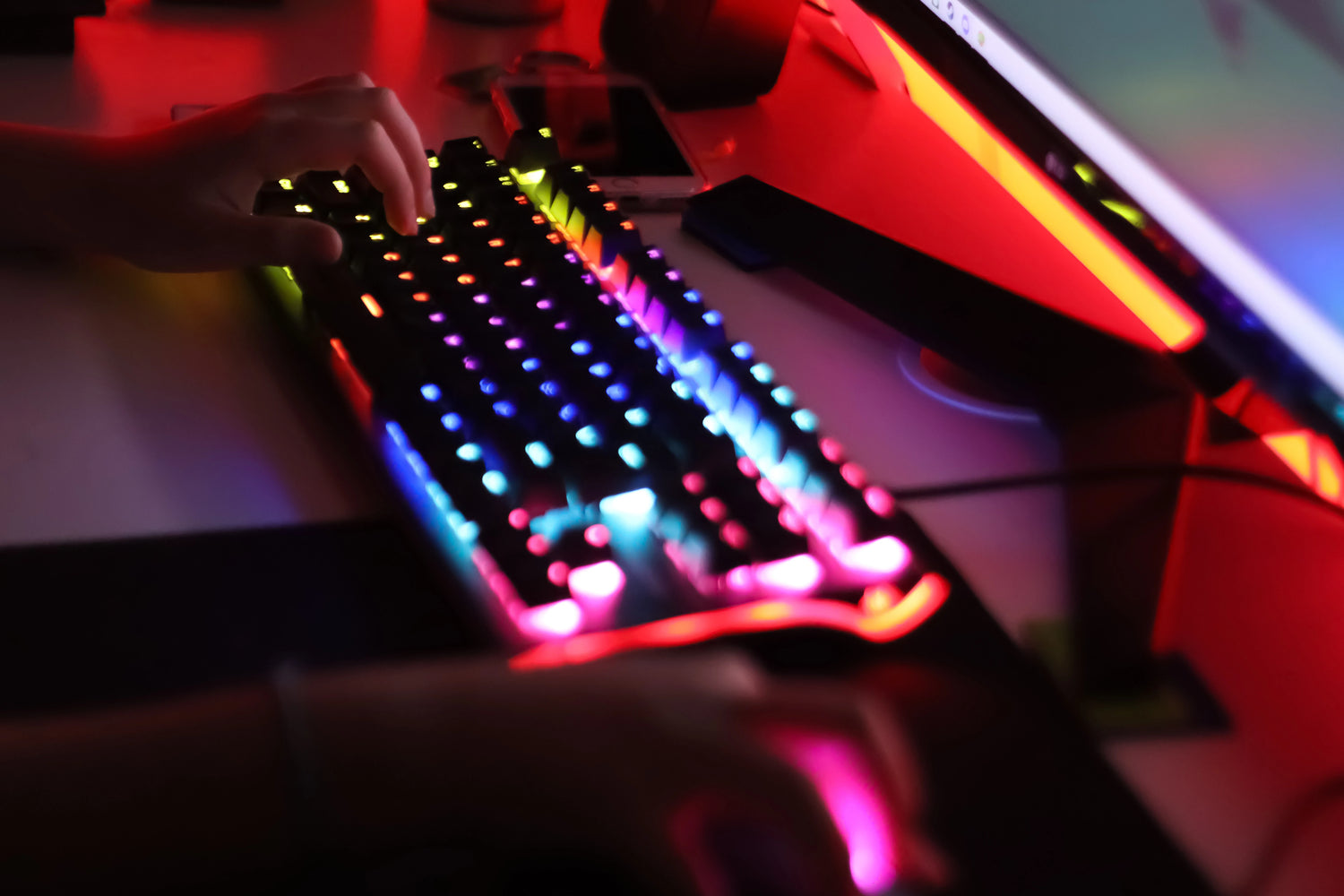 Gamer mit Headset an einem farbenfrohen RGB-Gaming-Setup beim Spielen am PC.