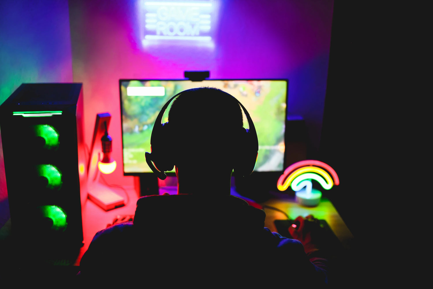 Gamer am Schreibtisch mit RGB-Beleuchtung und Headset beim Spielen eines Strategiespiels.